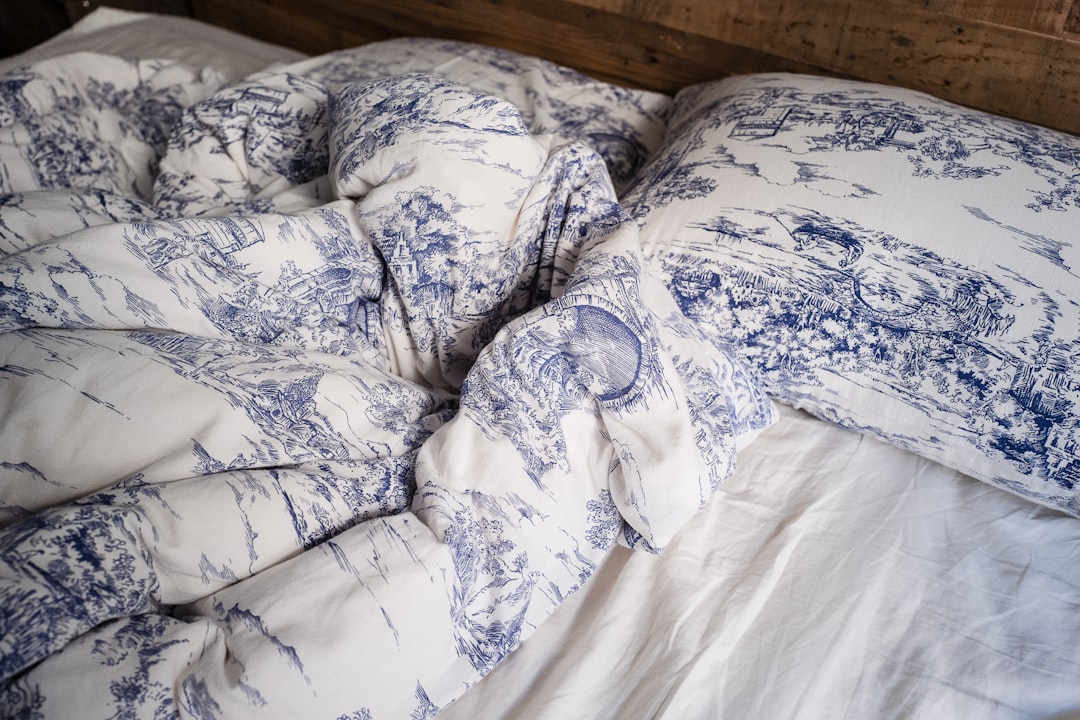 an unmade bed with white sheets and pillows