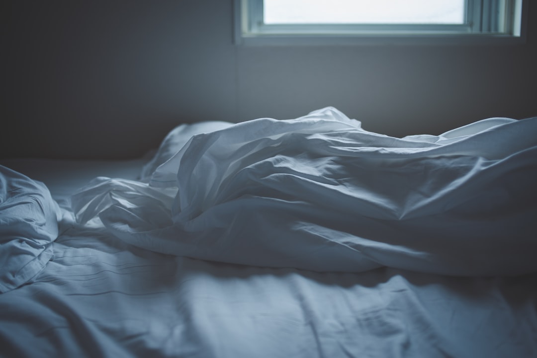 gray bedding beside window blinds